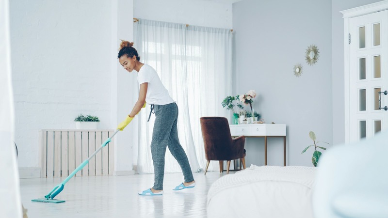 A cleaner mopping the floor of a bright living room